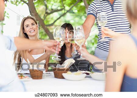 Friends toasting each other outdoors View Large Photo Image Stock Image - Friends toasting each other outdoors. Fotosearch