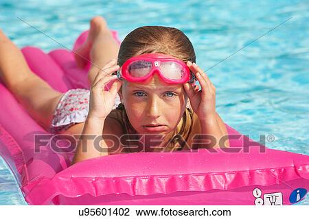 Stock Image - Girl floating on raft in swimming pool. Fotosearch
