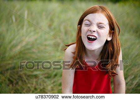 Stock Image - Girl grimacing in tall grass. Fotosearch