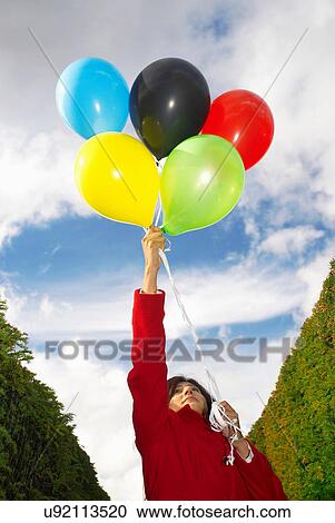 Stock Image - Girl holding balloons in olympic colours. Fotosearch