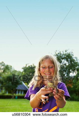 Picture - Girl holding frog in backyard. Fotosearch