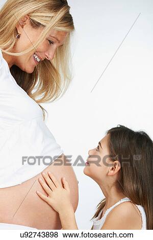 Girl hugging pregnant mother's belly View Large Photo Image Stock Photo - Girl hugging pregnant mother's belly. Fotosearch