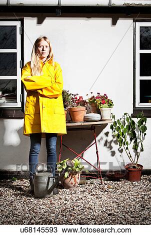 Girl in raincoat by potted plants View Large Photo Image Stock Image - Girl in raincoat by potted plants. Fotosearch