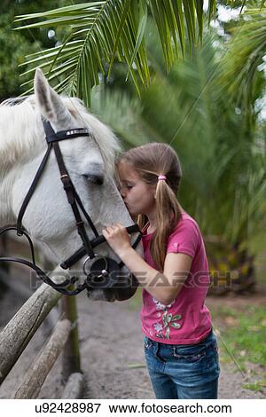 Stock Photo - Girl kissing horse in yard. Fotosearch