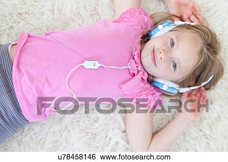 Girl listening to headphones on carpet View Large Photo Image Stock Photograph - Girl listening to headphones on carpet. Fotosearch