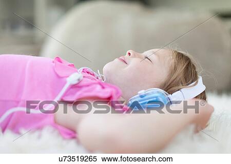 Girl listening to headphones on carpet View Large Photo Image Stock Photography - Girl listening to headphones on carpet. Fotosearch