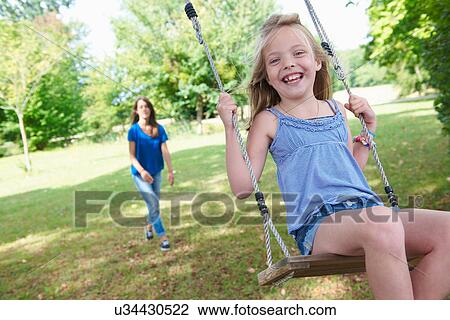 Girl playing on swing in backyard View Large Photo Image Stock Image - Girl playing on swing in backyard. Fotosearch