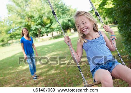 Stock Photo - Girl playing on swing in backyard. Fotosearch