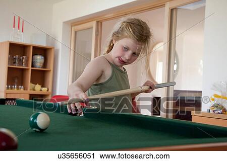Stock Image - Girl playing pool in game room. Fotosearch