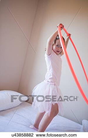 Stock Image - Girl playing with hula hoop in bedroom. Fotosearch
