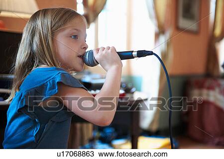 Stock Image - Girl singing into microphone. Fotosearch