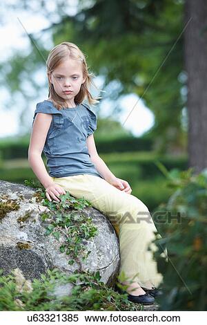 Stock Photography - Girl sitting on rock outdoors. Fotosearch