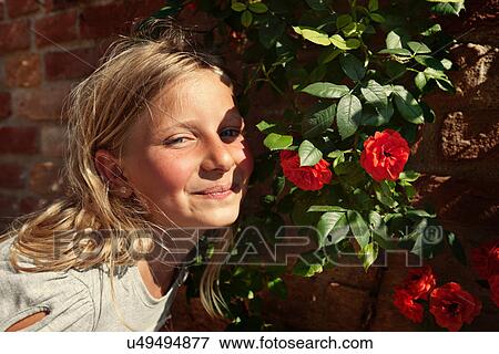 Stock Photo - Girl smelling flowers outdoors. Fotosearch