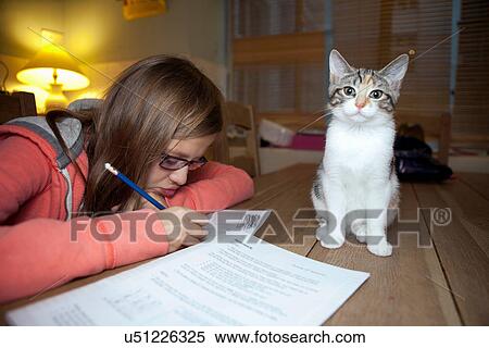 Stock Photography - Girl studying with cat on table. Fotosearch