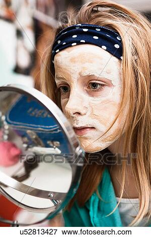 Stock Photo - Girl using face mask in bedroom. Fotosearch