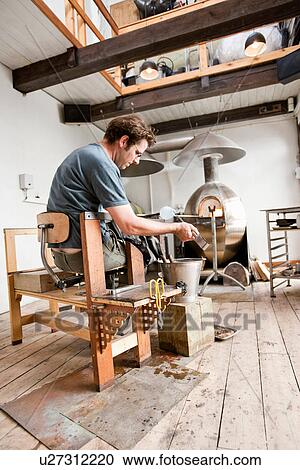 Stock Image - Glassblower shaping hot glass. Fotosearch