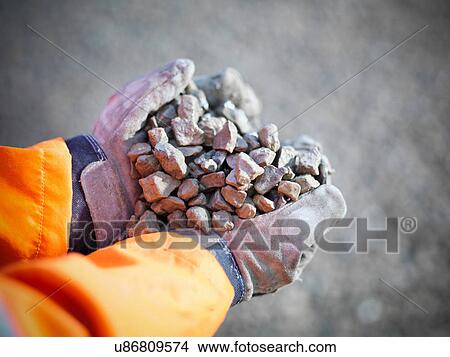 Picture - Gloved hands holding crushed stones in quarry site. Fotosearch