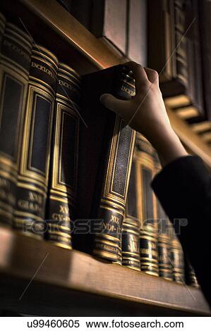 Stock Photography - Hand pulling book from bookshelf. Fotosearch