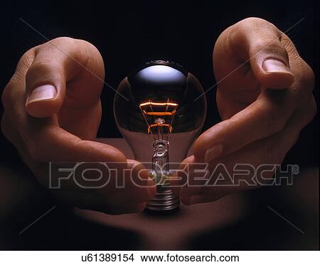 Picture - Hands cupping glowing light bulb. Fotosearch