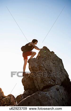 Stock Photo - Hiker climbing rocks on hill. Fotosearch