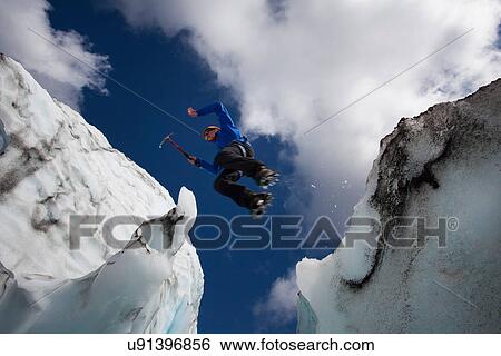 Hiker jumping in between glaciers View Large Photo Image Stock Photograph - Hiker jumping in between glaciers. Fotosearch