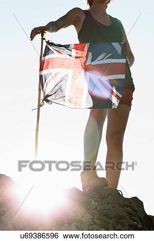 Stock Photograph - Hiker planting Union Jack flag. Fotosearch