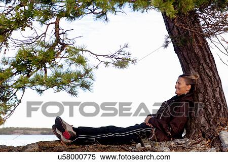 Stock Photography - Hiker relaxing by tree. Fotosearch