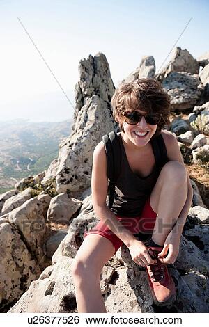 Stock Photograph - Hiker tying her shoe on rocks. Fotosearch