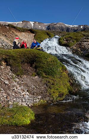 Picture - Hikers resting by waterfall. Fotosearch