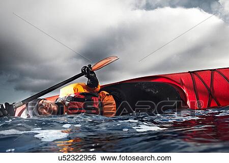 Stock Photograph - Kayaker flipped over in water. Fotosearch