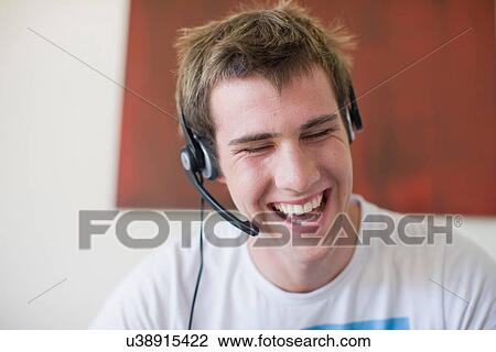 Stock Image - Laughing teenage boy wearing headset. Fotosearch