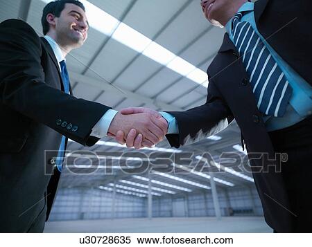 Low angle view of property managers shaking hands in finished factory building View Large Photo Image Stock Photography - Low angle view of property managers shaking hands in finished factory building. Fotosearch