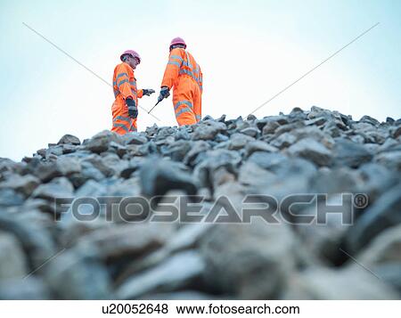 Low angle view of quarryman and assistant standing on stockpile of quarried stone View Large Photo Image Stock Photo - Low angle view of quarryman and assistant standing on stockpile of quarried stone. Fotosearch