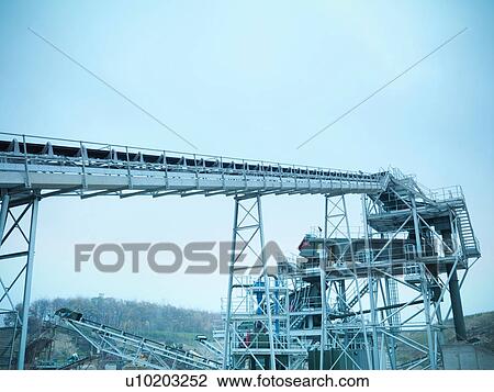 Stock Image - Low angle view of screening conveyor at quarry site. Fotosearch