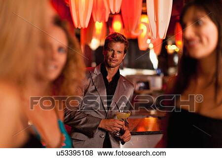 Stock Photo - Man admiring women in bar. Fotosearch