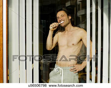 Man brushing his teeth at window View Large Photo Image Stock Photo - Man brushing his teeth at window. Fotosearch