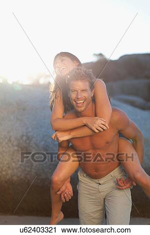 Stock Image - Man carrying girlfriend piggyback. Fotosearch
