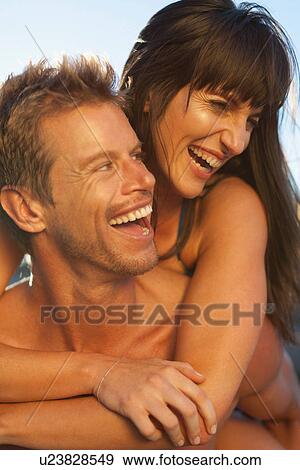 Stock Photo - Man carrying girlfriend piggyback. Fotosearch