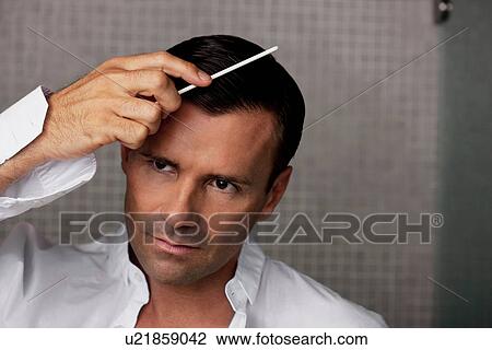 Man combing his hair in bathroom View Large Photo Image Stock Image - Man combing his hair in bathroom. Fotosearch