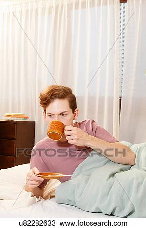 Stock Image - Man drinking coffee in bed. Fotosearch