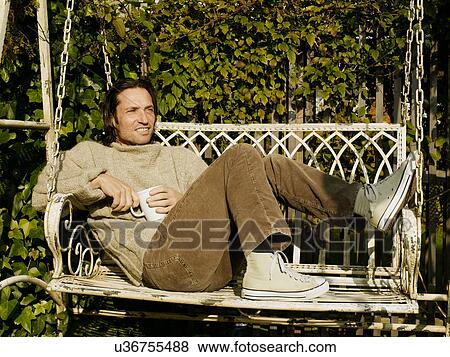 Stock Photo - Man drinking coffee in chair swing. Fotosearch