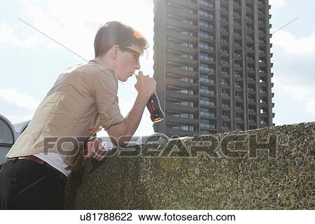 Stock Image - Man drinking soda on balcony. Fotosearch