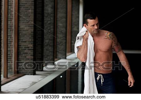 Stock Photo - Man drying off by indoor pool. Fotosearch