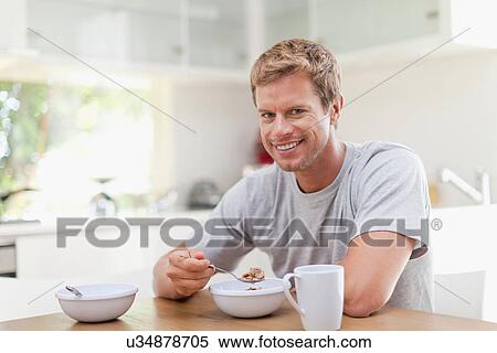 Stock Photography - Man eating breakfast in kitchen. Fotosearch