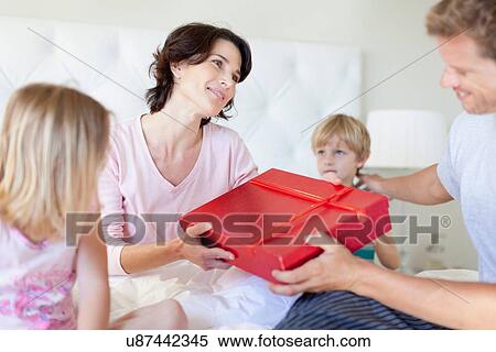 Man giving wife present in bed View Large Photo Image Stock Photography - Man giving wife present in bed. Fotosearch