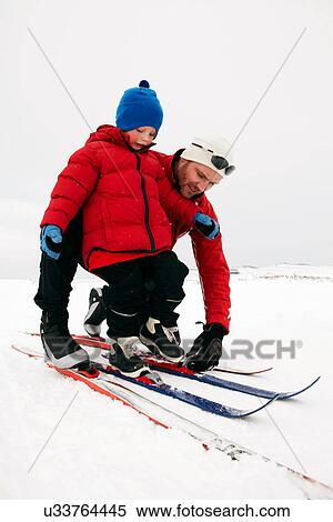 Man helping child put on skis in snow View Large Photo Image Stock Photography - Man helping child put on skis in snow. Fotosearch