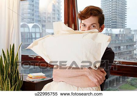 Stock Photography - Man hugging pillows near window. Fotosearch