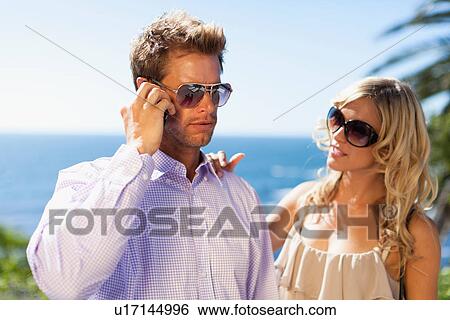 Stock Photograph - Man ignoring girlfriend for cell phone. Fotosearch