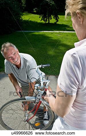 Stock Photograph - Man inflating woman's bike tire. Fotosearch