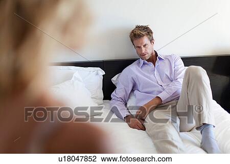 Stock Image - Man laying on bed looking at girlfriend. Fotosearch